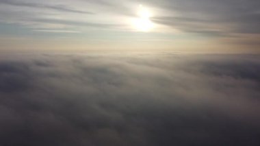 Bulutlarda uçuyor. Sabah güneşi ve sisli havada.
