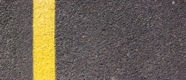 Asfalt desenli, sol tarafında sarı bir çizgi var. İşaretli yol yüzeyi