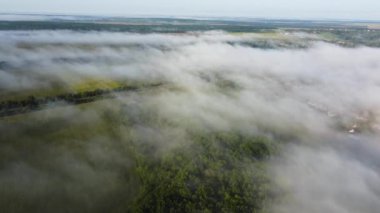 İHA siste uçuyor. Doğa ve küçük bir yerleşim yeri. Hava görüntüsünden sabah manzarası.