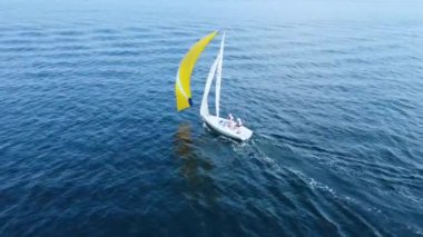 Deniz yelkenlisi. Mavi denizde yelken açan sarı yelkenli güzel beyaz bir yat.