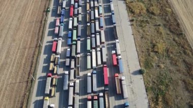 İHA, liman terminalinde boşaltılmayı bekleyen uzun bir kamyon hattının üzerinden uçuyor. Diğer ülkelere tahıl ihracatı. Lojistik şirketi.