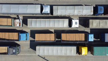 Terminalde kuyrukta bekleyen kamyonların üst görüntüsü. Traktörlerle kargo taşımacılığı. Otoparkta lojistik nakliye..