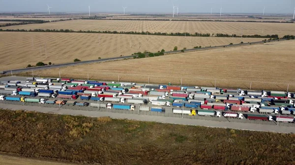 Trucks with trailers stand in a long queue at the port terminal for unloading grain