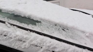 Bir kar fırtınasını takiben, kar yağışlı bir arabanın ön camını temizleyen adamlar. Aracı kış koşullarında güvenli sürüş için hazırlıyorum.