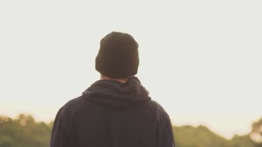 Sporcu siyah giysileri, ufukta beyaz gökyüzüne, bokeh ağaçlarına bakıyor..