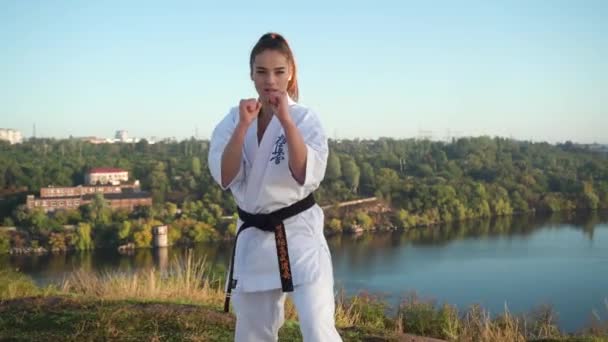 Tłumaczenie: "Kyokushinkai". młoda kobieta biały kimono demonstruje karate technika na tle natury — Wideo stockowe