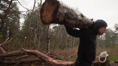 Kaslı sporcu ağır yük kaldırıyor, ormanda kütük tutuyor. Sonbaharda