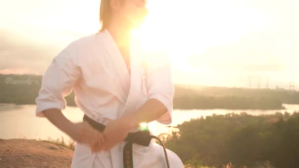 Translation: Kyokushinkai . young woman white kimono demonstrates karate technique against backdrop nature — Stock Video