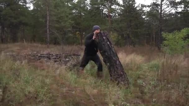 Hij gaat sporten in het bos. Duwt groot, zwaar hout, boom. Motivatie — Stockvideo