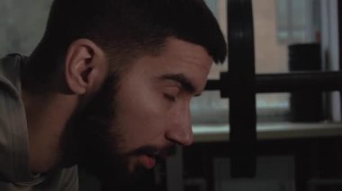 Öğleden sonra dersten sonra spor salonunda halterli bir adam pencerenin arkasına yaslanmış.