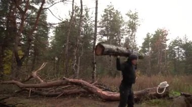 Kaslı sporcu ağır yük kaldırıyor, ormanda kütük tutuyor. Sonbaharda