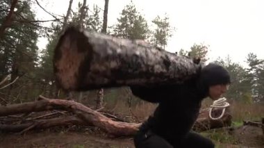 Kaslı sporcu ağır yük kaldırıyor, ormanda kütük tutuyor. Sonbaharda