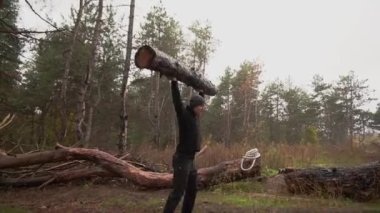 Kaslı sporcu ağır yük kaldırıyor, ormanda kütük tutuyor. Sonbaharda