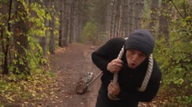 Kaslı sporcu ağır yük kaldırıyor, ormanda kütük tutuyor. Sonbaharda