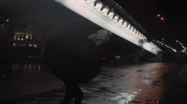 Şemsiye yağmuruyla dans eden adam, köprünün yanındaki gece merkezi metropolü.