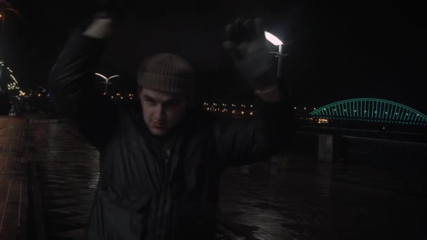 O cara está brincando com um guarda-chuva, à noite na cidade, na chuva — Vídeo de Stock