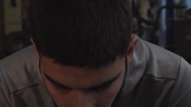 Eski bir spor salonunda antrenmandan sonra genç bir adamın yüzüne yakın çekim.