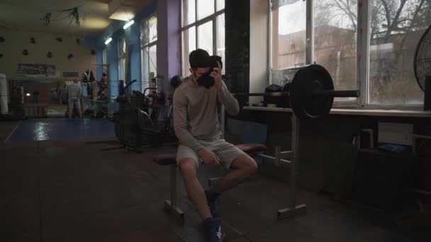 Хлопець після тренування в спортзалі з штангою потіє рушником — стокове відео