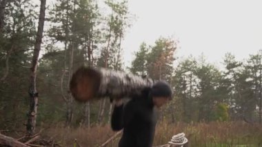 Kaslı sporcu ağır yük kaldırıyor, ormanda kütük tutuyor. Sonbaharda