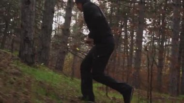 Sporcu karanlık sonbahar ormanlarında ağaçların arasından koşar.