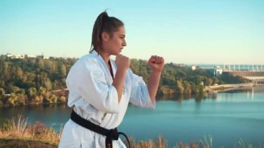 Sabahın erken saatlerinde genç bir kadın sokakta karate yapıyor.