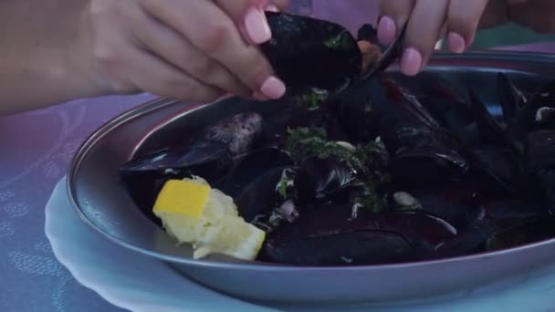 Smiling girl correctly opens, takes out, eats, chews boiled mussels from shell — Stock Video