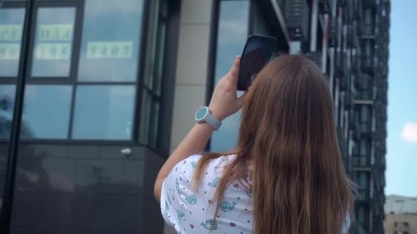 Jong meisje maakt video voor een netwerk. video van hoog nieuw gebouw, dan ruïnes. zomerdag, heldere lucht — Stockvideo