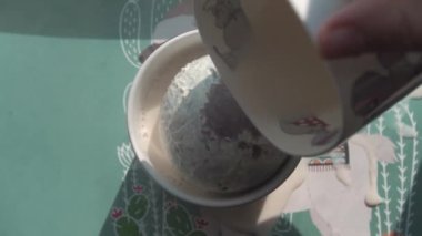 Sıcak süt bir fincanda çikolata topuna dökülür.