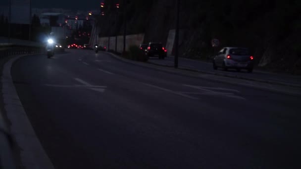 Дорога, вид на рухливі автомобілі вздовж схилу, сутінки, вогні, фари ввімкнені, за горою — стокове відео