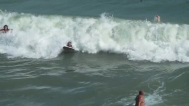 ODESSA, UKRAINE - 27 AĞUSTOS 2020: Yandan çekilen genç kızlar büyük dalgalara binmekten hoşlanırlar Karadeniz