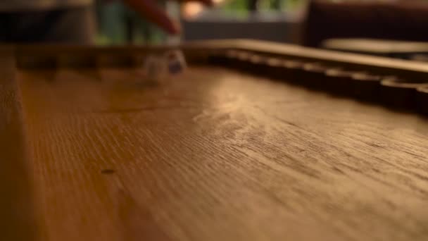 Une main mans lance des dés colorés sur une planche de backgammon en bois — Video