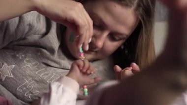 Genç neo annenin otantik yakın plan çekimi bir sabah bebek odasında yeni doğmuş bebeğiyle oynuyor. 8K 'de çekilmiş. Çocuk, bebek, ebeveynlik, çocukluk, hayat, annelik, annelik kavramı