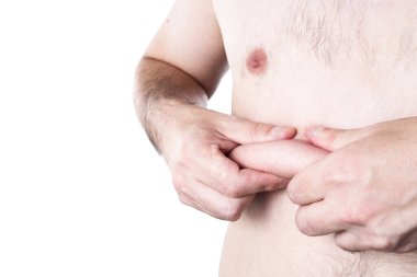 Beyaz arka planda şişman bir adam. Elleri karnına dokunan bir adamın aşırı vücut ağırlığı. Adam kilo vermiş. Kopya alanı ile obezite veya kilo kaybı kavramı