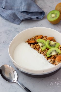 Beyaz yoğurtlu müsli, kivi ve hindistan cevizi. Sağlıklı beslenme. Vejetaryen yemeği. Kahvaltı.