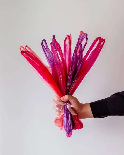 The hand holds a bouquet of pink packages . Humor. Gift