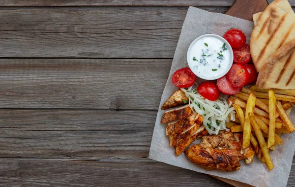 Greek dish gyros with chicken, french fries, tomatoes, onions and pita. Greek cuisine