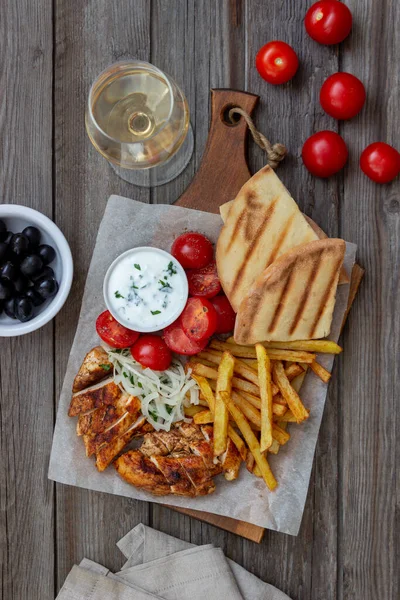 Greek dish gyros with chicken, french fries, tomatoes, onions and pita. Greek cuisine