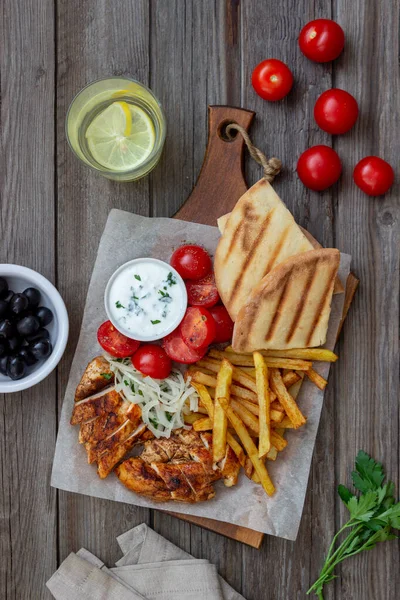 Greek dish gyros with chicken, french fries, tomatoes, onions and pita. Greek cuisine