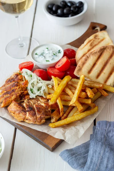 Greek dish gyros with chicken, french fries, tomatoes, onions and pita. Greek cuisine