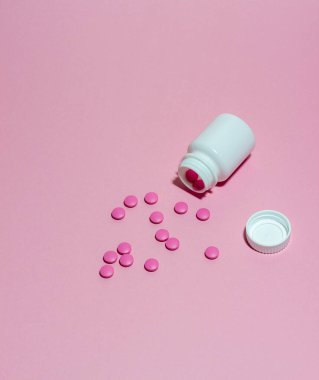 Pembe arka planda tabletleri olan beyaz bir kavanoz. Sağlığa. İlaç.