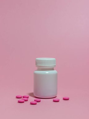 Pembe arka planda tabletleri olan beyaz bir kavanoz. Sağlığa. İlaç.
