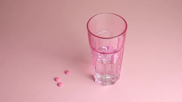 Elderly womans hand takes pills and water against a pink background. Medicine. Disease. — Stock Video