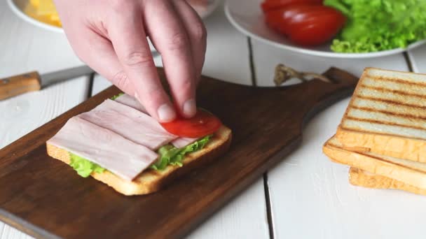 Processen att göra en smörgås med sallad, tomat, skinka och ost. Amerikanskt kök. Snabbmat. Matlagning. — Stockvideo