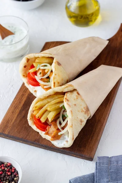 Greek dish gyros with chicken, french fries, tomatoes, onions and pita. Greek cuisine