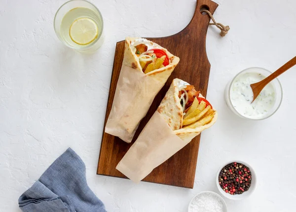 Greek dish gyros with chicken, french fries, tomatoes, onions and pita. Greek cuisine