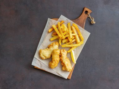 Koyu bir arka planda balık ve patates kızartması. İngiliz fast food. Yemek tarifleri. Atıştırmalıktan biraya. Geleneksel İngiliz yemekleri.