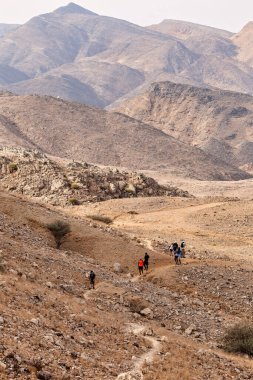 Eylül 2020 civarı. Birkaç kişi Muscat, Umman dağlarında bir yürüyüş sırasında dar bir patika boyunca yürür..