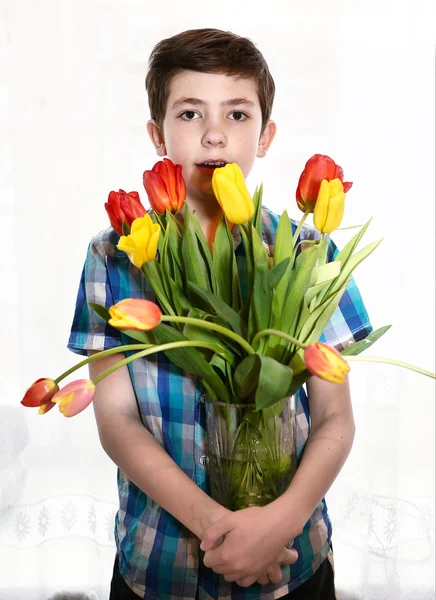 Preteen handsome boy with tulip flowers — Stockfoto