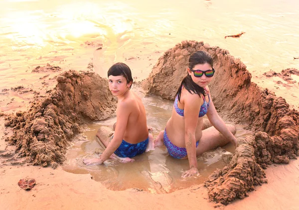 Adolescente menino e menina jogar com areia na praia — Fotografia de Stock