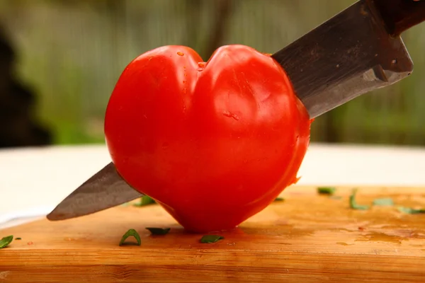 Hjärtformade tomat skärs med kniv — Stockfoto